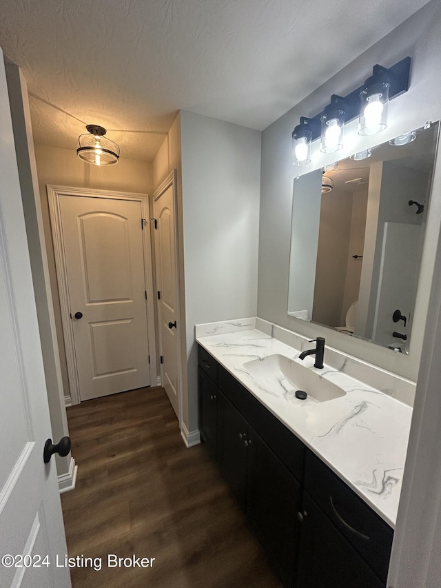 bathroom with hardwood / wood-style floors, vanity, a textured ceiling, and toilet