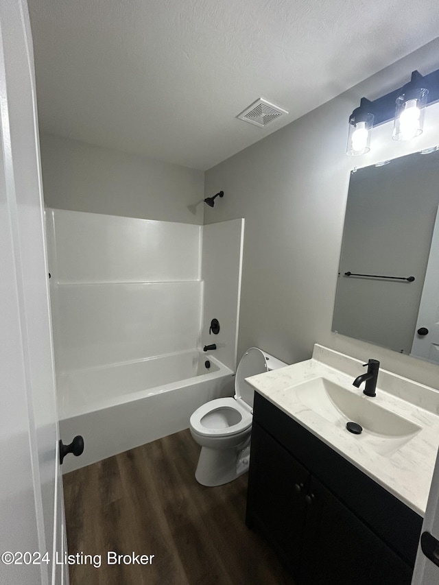 full bathroom featuring tub / shower combination, a textured ceiling, vanity, hardwood / wood-style flooring, and toilet