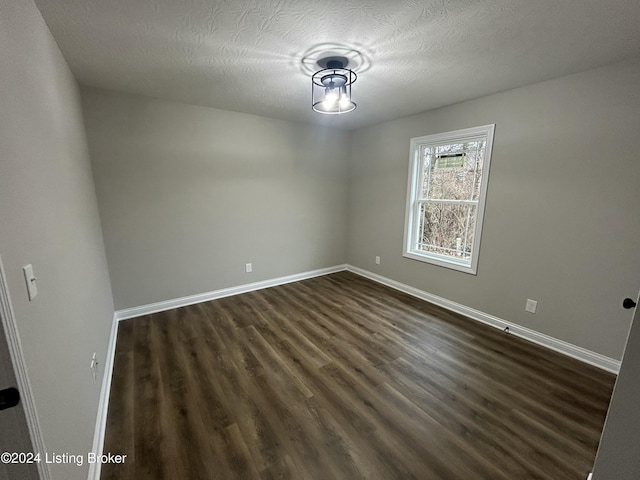 empty room featuring dark hardwood / wood-style flooring and a textured ceiling