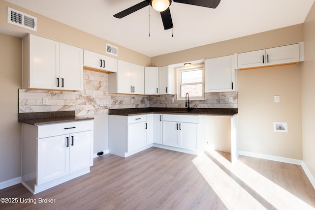 kitchen featuring light hardwood / wood-style floors, white cabinetry, tasteful backsplash, and sink