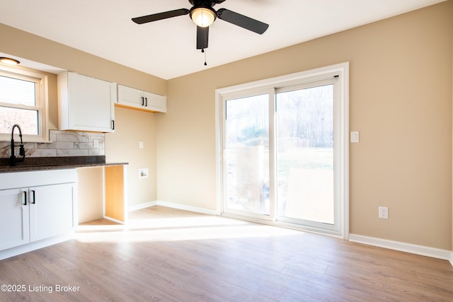 kitchen featuring backsplash, white cabinetry, sink, and light wood-type flooring