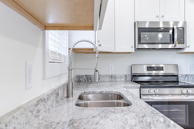 kitchen featuring light stone countertops, sink, white cabinets, and appliances with stainless steel finishes