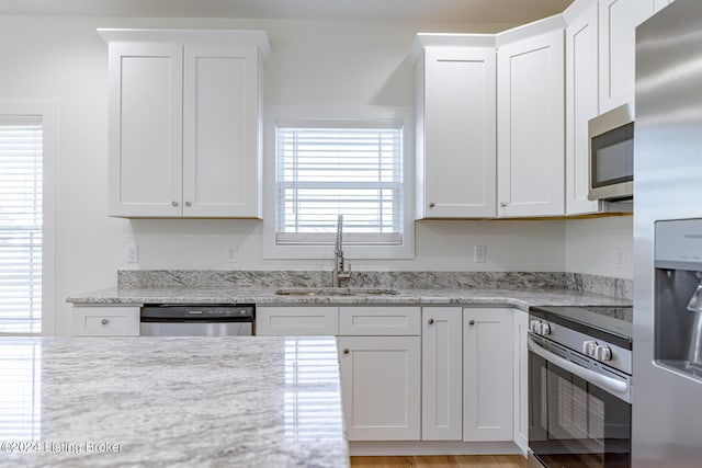 kitchen featuring white cabinetry, sink, stainless steel appliances, and plenty of natural light