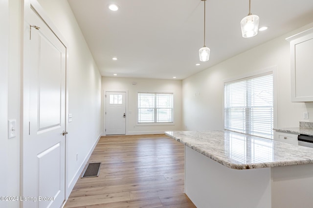 kitchen with white cabinets, light stone countertops, light hardwood / wood-style floors, and hanging light fixtures