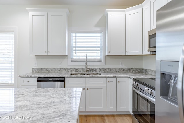 kitchen with light stone counters, sink, white cabinets, and stainless steel appliances