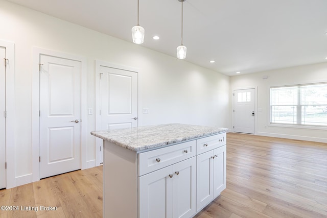 kitchen with light stone counters, a kitchen island, decorative light fixtures, light hardwood / wood-style flooring, and white cabinetry