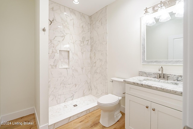 bathroom with vanity, toilet, wood-type flooring, and tiled shower