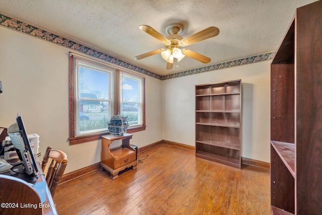 misc room with a textured ceiling, light hardwood / wood-style floors, and ceiling fan