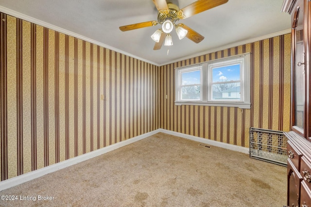 carpeted empty room featuring ceiling fan and crown molding