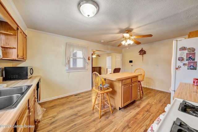 kitchen featuring a kitchen breakfast bar, light hardwood / wood-style flooring, white refrigerator, a kitchen island, and ornamental molding