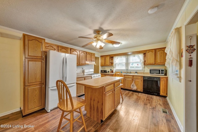 kitchen with sink, light hardwood / wood-style flooring, white appliances, a kitchen island, and ornamental molding