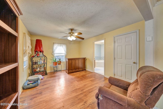 sitting room featuring ceiling fan, a textured ceiling, and light wood-type flooring