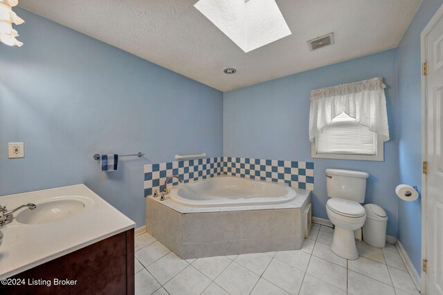 bathroom featuring tile patterned floors, toilet, tiled bath, and a skylight