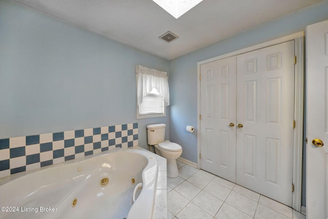 bathroom featuring tile patterned flooring, a bathing tub, toilet, and a skylight