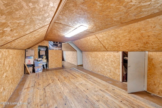 additional living space with hardwood / wood-style flooring and vaulted ceiling