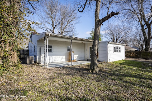 back of property with a yard and central AC unit