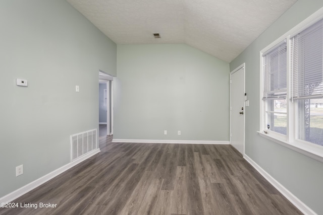 empty room with dark hardwood / wood-style floors, lofted ceiling, and a textured ceiling