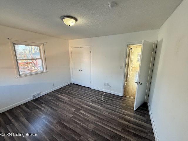 unfurnished bedroom with dark hardwood / wood-style floors, a textured ceiling, and a closet