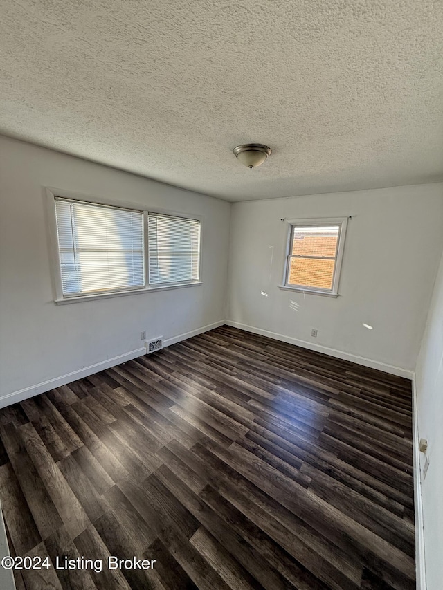 spare room featuring a textured ceiling and dark hardwood / wood-style flooring