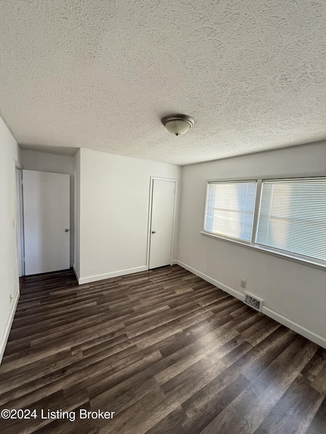 unfurnished room featuring a textured ceiling and dark wood-type flooring