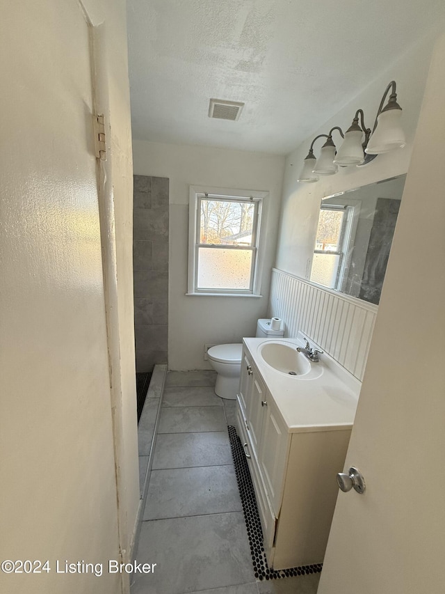 bathroom featuring vanity, tile patterned flooring, toilet, a textured ceiling, and walk in shower