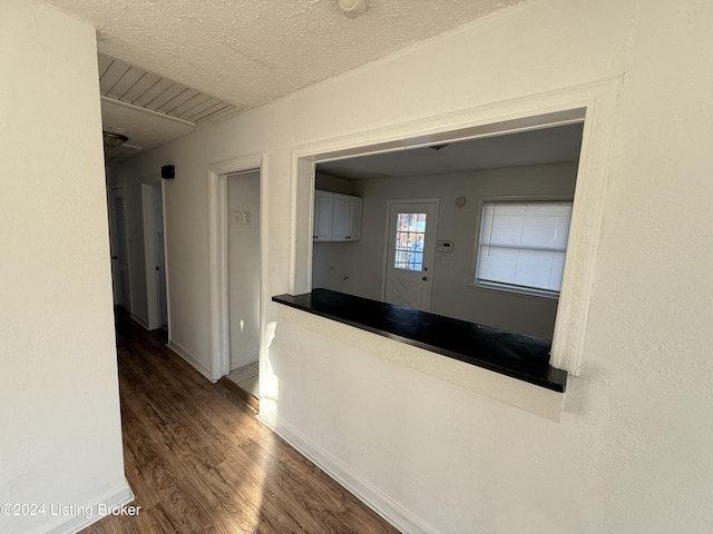 hallway with a textured ceiling and hardwood / wood-style flooring