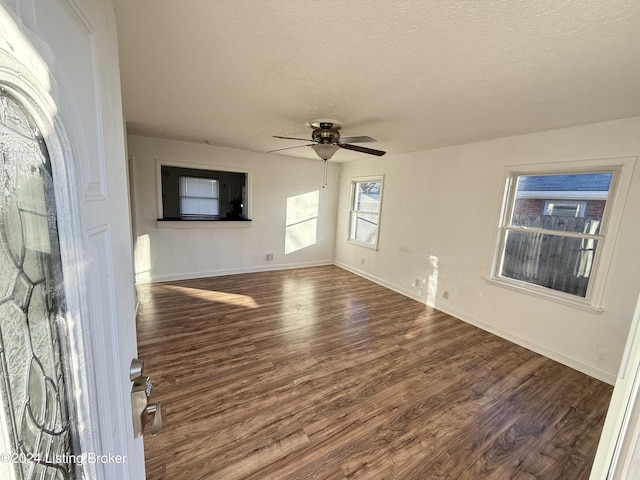 unfurnished living room featuring dark hardwood / wood-style floors, ceiling fan, and a textured ceiling