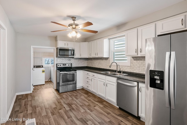 kitchen with appliances with stainless steel finishes, tasteful backsplash, sink, white cabinets, and independent washer and dryer