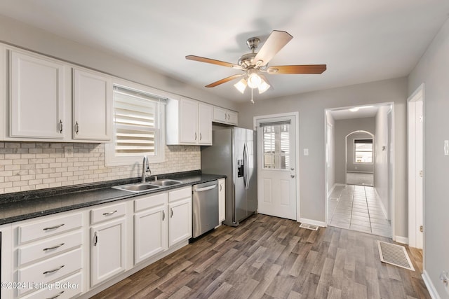 kitchen with dark wood-type flooring, sink, white cabinets, stainless steel appliances, and backsplash