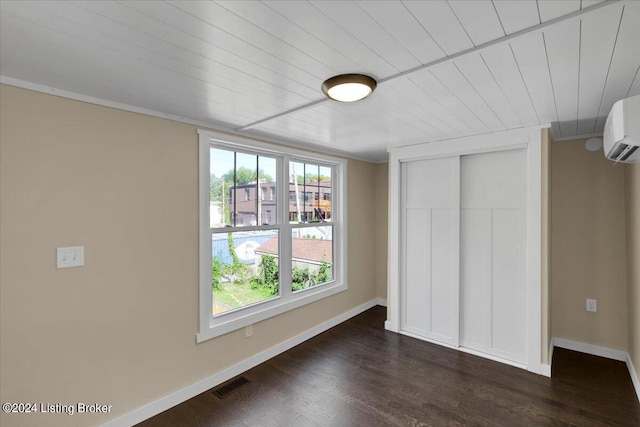 unfurnished bedroom featuring a wall unit AC, a closet, and dark hardwood / wood-style floors