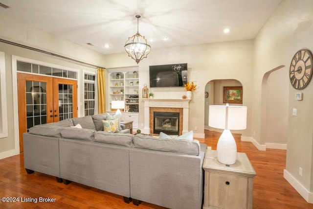 living room with french doors, hardwood / wood-style flooring, an inviting chandelier, and built in shelves