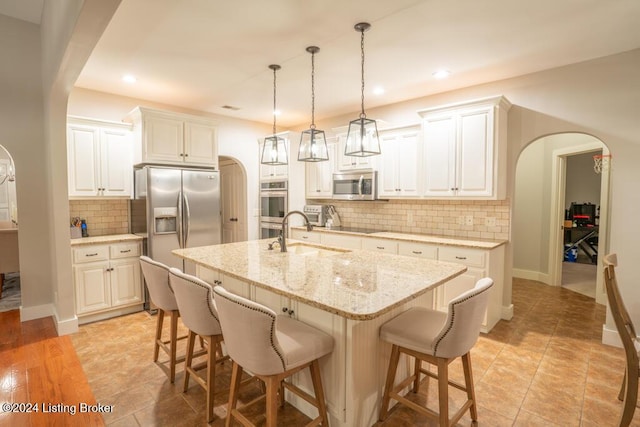 kitchen featuring tasteful backsplash, a center island with sink, white cabinets, and appliances with stainless steel finishes