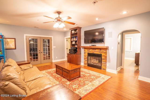 living room with a fireplace, french doors, light hardwood / wood-style floors, and ceiling fan