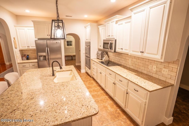 kitchen with light stone counters, sink, decorative light fixtures, and appliances with stainless steel finishes