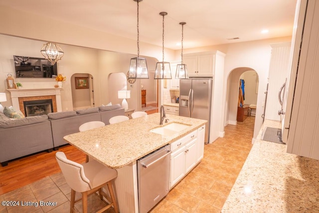 kitchen featuring a kitchen island with sink, white cabinets, a kitchen breakfast bar, sink, and appliances with stainless steel finishes