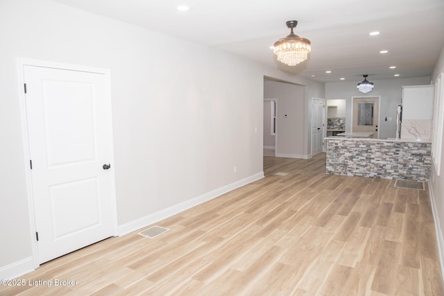 unfurnished living room with a chandelier and light hardwood / wood-style floors