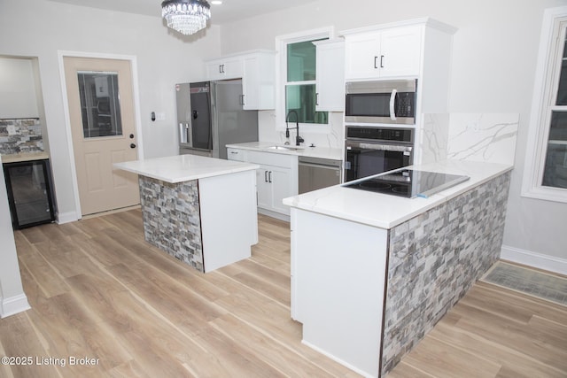 kitchen with white cabinetry, sink, a center island, light hardwood / wood-style floors, and black appliances