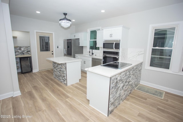 kitchen featuring black appliances, kitchen peninsula, white cabinets, and a center island