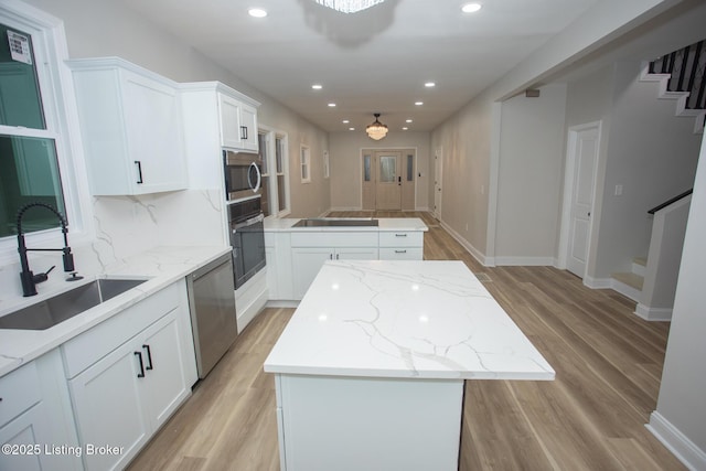 kitchen with white cabinetry, sink, a center island, black appliances, and light stone countertops