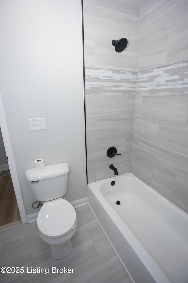 bathroom featuring toilet and tiled shower / bath combo