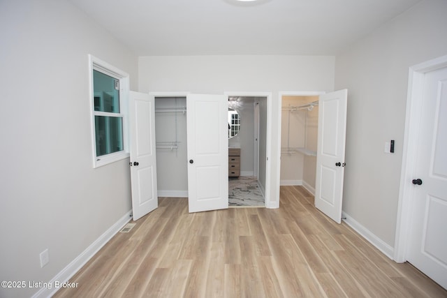 unfurnished bedroom featuring light hardwood / wood-style flooring and a walk in closet