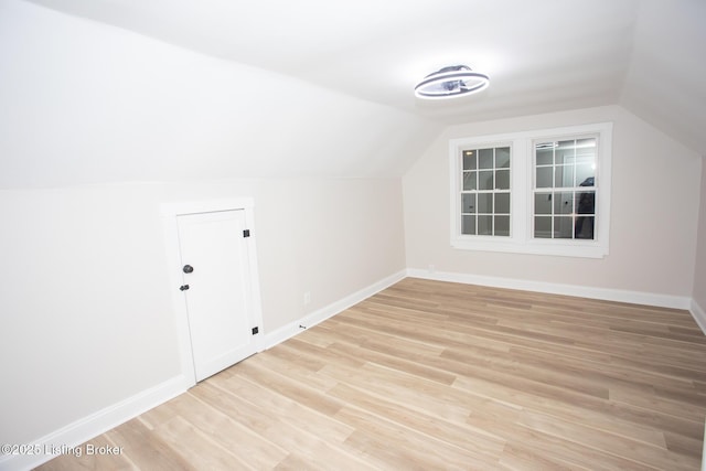 additional living space with vaulted ceiling and light wood-type flooring