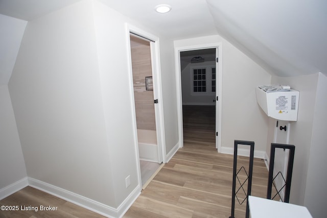 hall featuring lofted ceiling and light hardwood / wood-style flooring