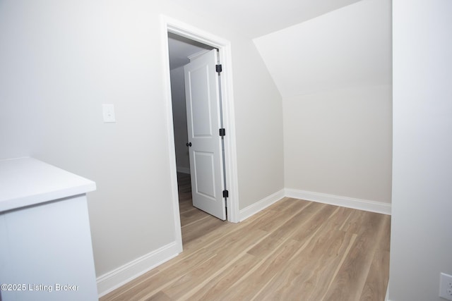 hallway with lofted ceiling and light hardwood / wood-style floors