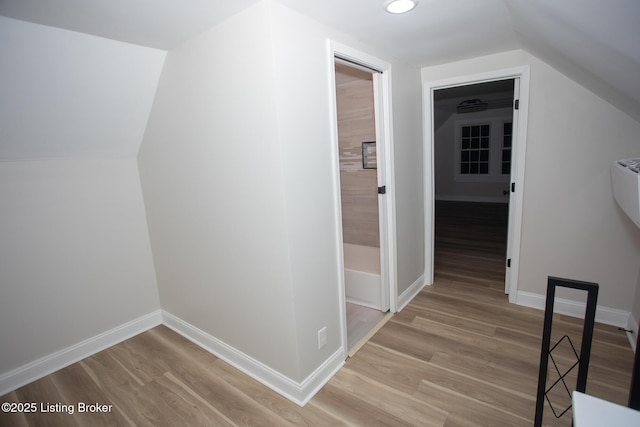 hall with vaulted ceiling and light hardwood / wood-style floors