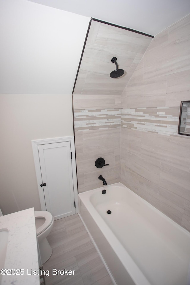 bathroom with tiled shower / bath combo and toilet