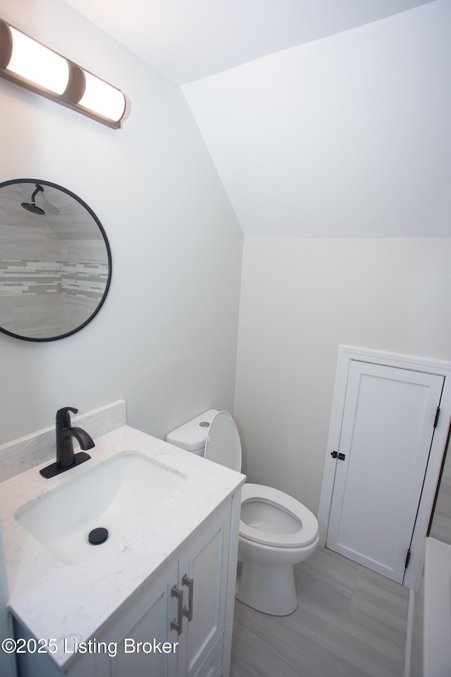 bathroom featuring vanity, lofted ceiling, and toilet