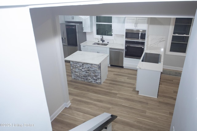 kitchen featuring sink, white cabinetry, hardwood / wood-style floors, a center island, and black appliances