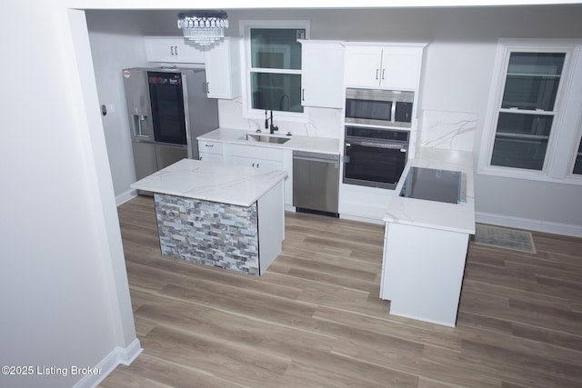 kitchen with sink, wood-type flooring, black appliances, a center island, and white cabinets