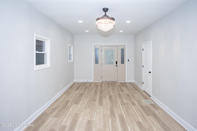 corridor with a notable chandelier and light wood-type flooring